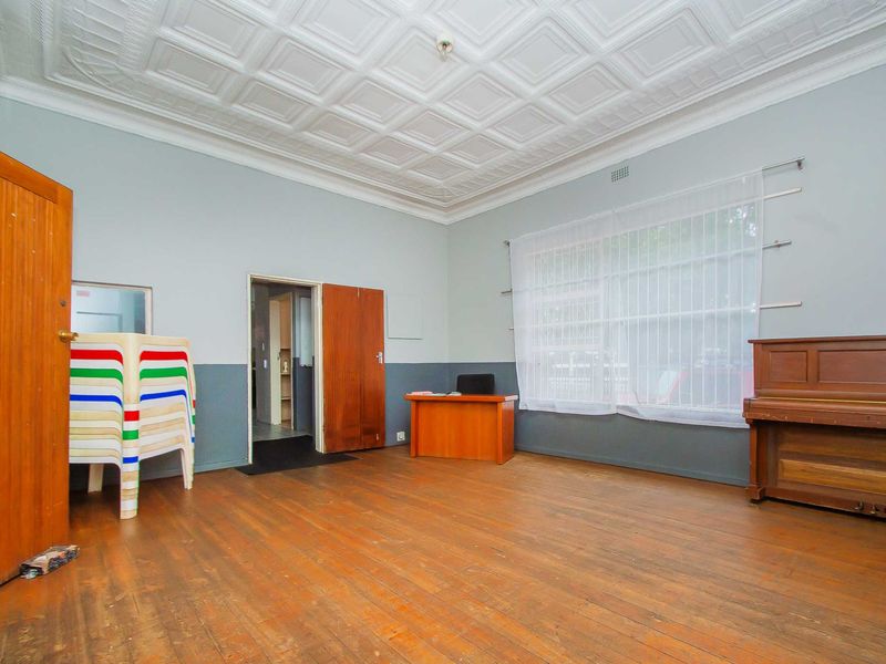 A spacious office area featuring original pressed metal ceilings, polished timber flooring, and classic timber door frames, offering a versatile commercial workspace.