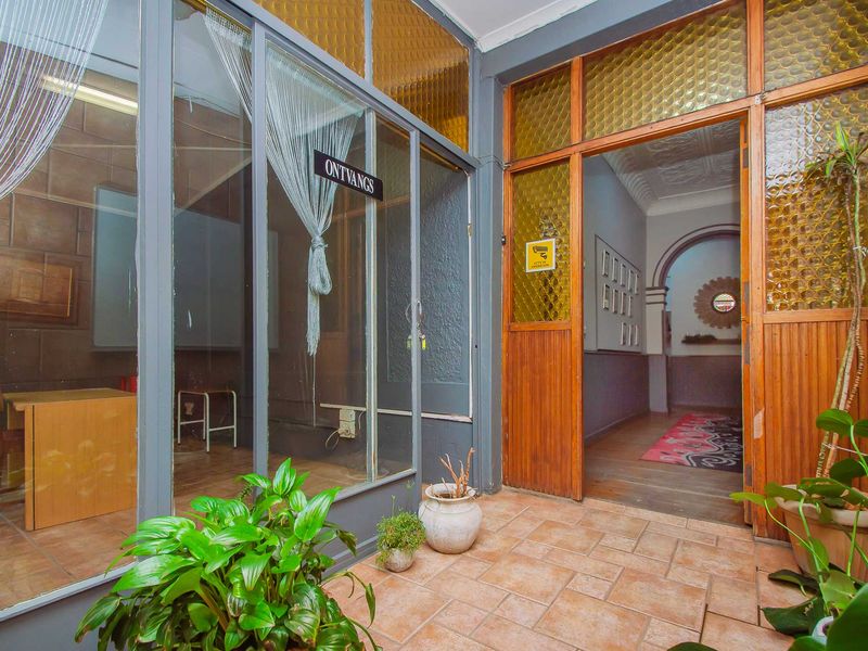 Entrance area featuring tiled flooring, a glass partition wall, and a wooden door frame with textured glass panels leading into the interior hallway.