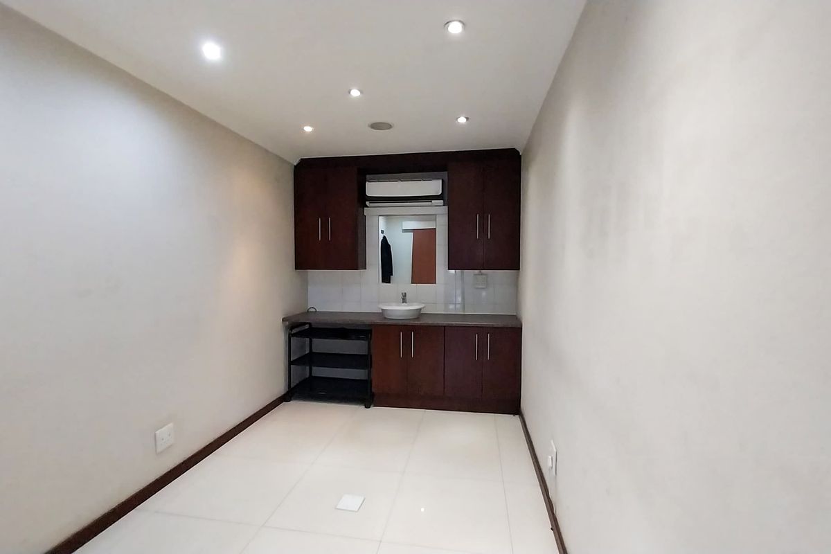 A compact kitchenette or utility area featuring dark wood cabinetry, a basin, and recessed ceiling lighting.