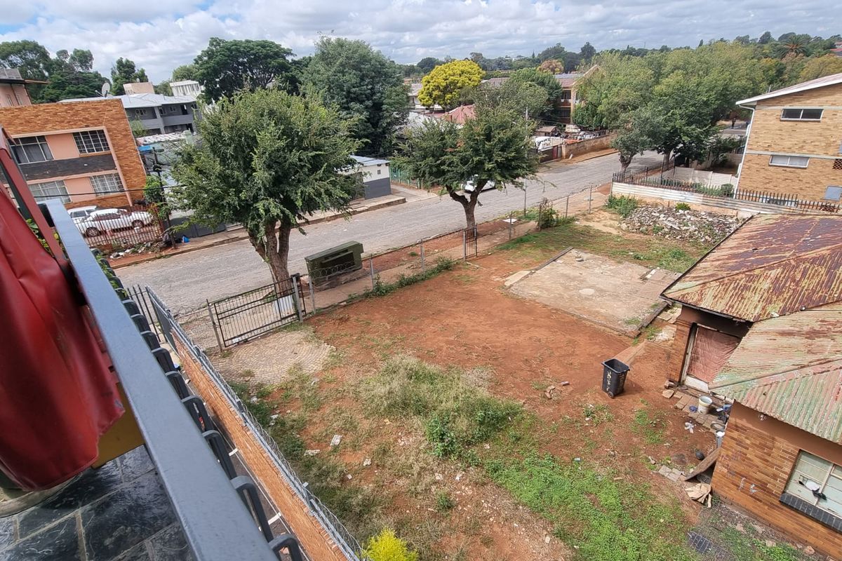 Elevated view overlooking a commercial property lot with a rusted metal roof structure, open dirt yard, and perimeter fencing.