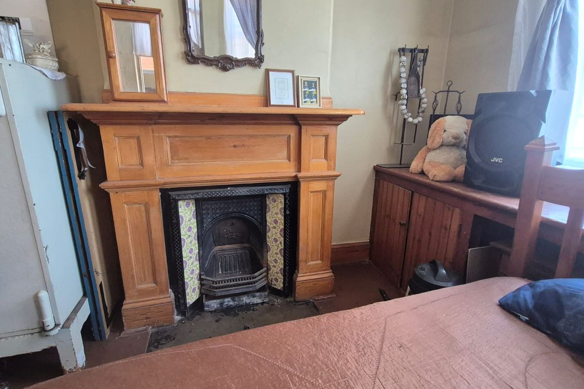 A bedroom featuring a traditional wooden fireplace mantel with a decorative cast iron insert and built-in wooden cabinetry.