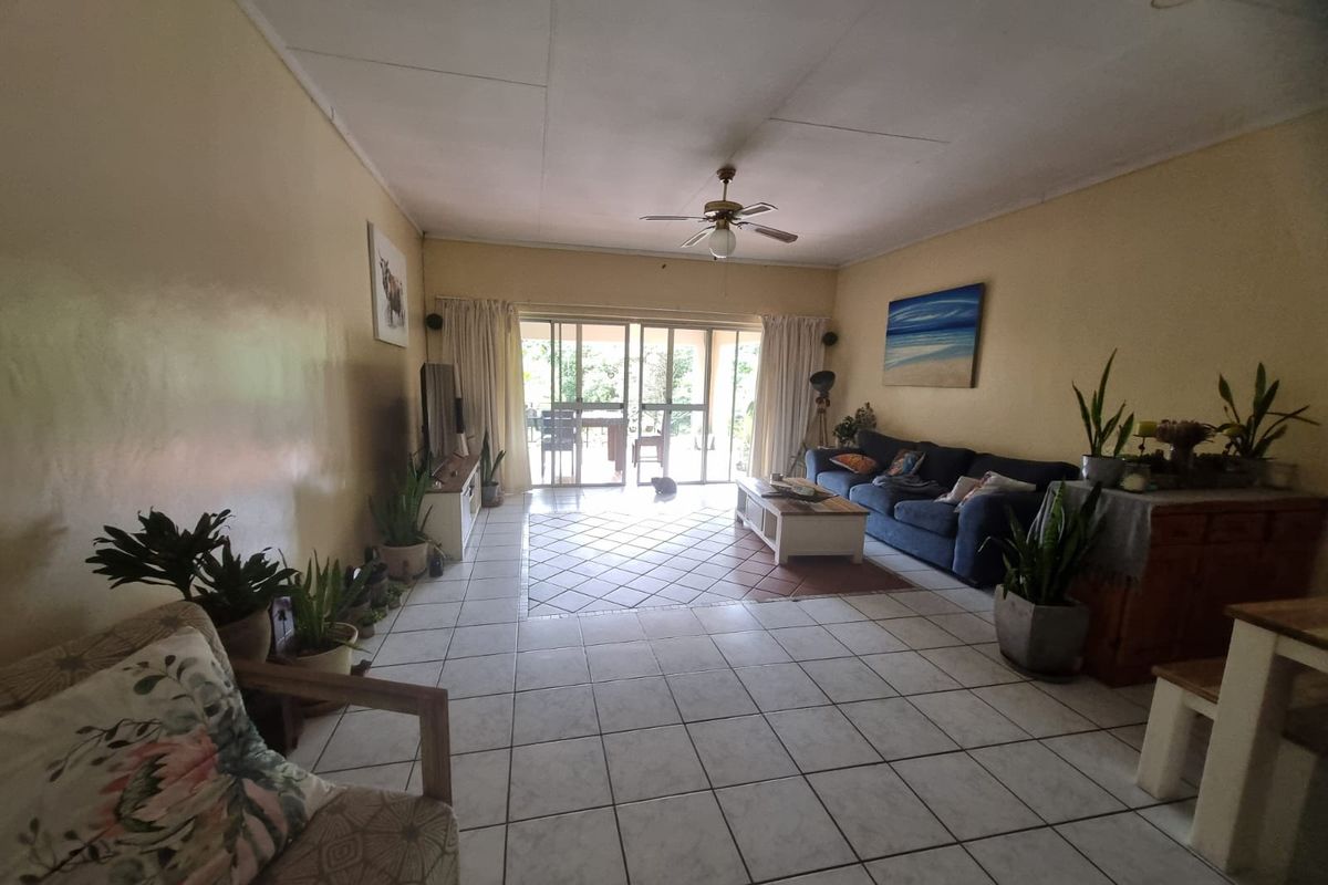 Spacious living room featuring tiled flooring, a ceiling fan, and large sliding glass doors that provide access to the outdoor patio area.