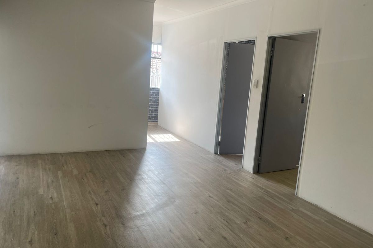 An empty interior space featuring light wood-look laminate flooring and two doorways leading to adjacent rooms.