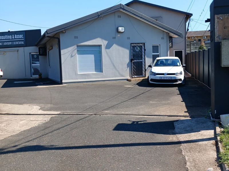 Front exterior view of the office property featuring a paved driveway, security gate, and building facade.