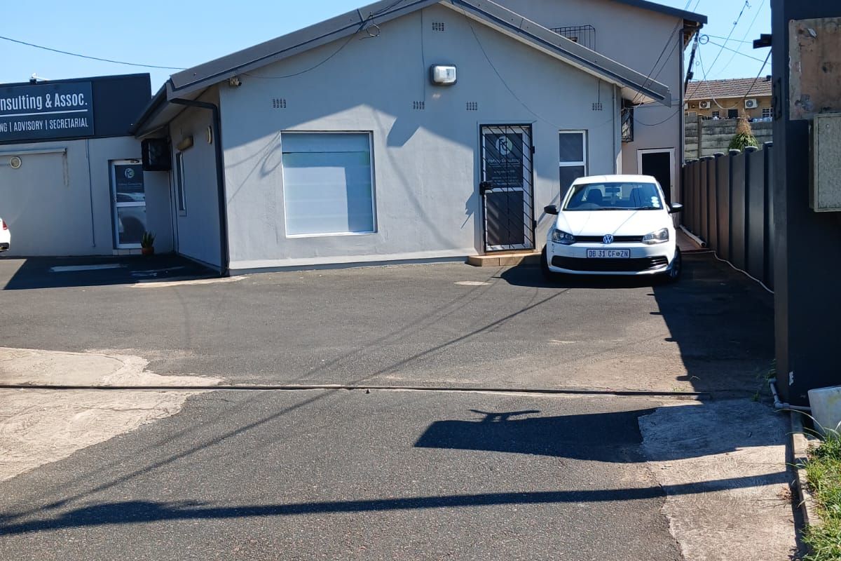 Front exterior view of the office property featuring a paved driveway, security gate, and building facade.