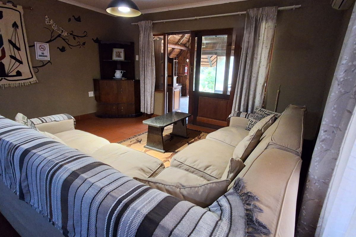 A cozy living room featuring tiled flooring, an air conditioning unit, and direct access to an outdoor area through a timber-framed door.