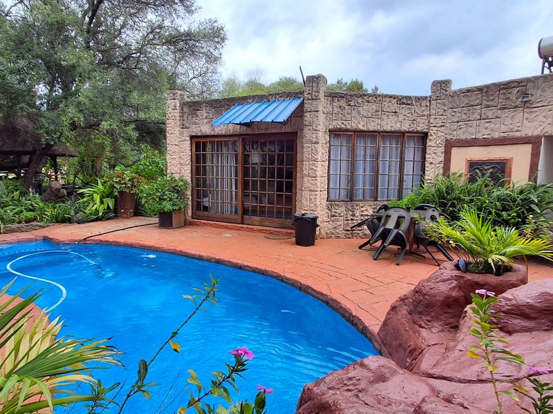 Outdoor pool area featuring a swimming pool with terracotta paving, stone-clad building exterior, and integrated solar water heating system.
