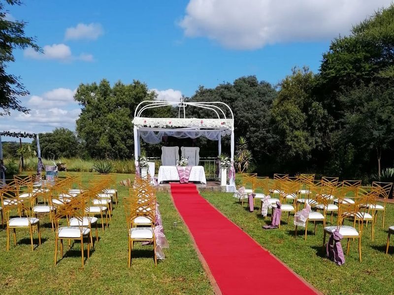 A well-maintained outdoor garden area featuring a permanent metal gazebo structure, suitable for events and ceremonies within the lodge grounds.