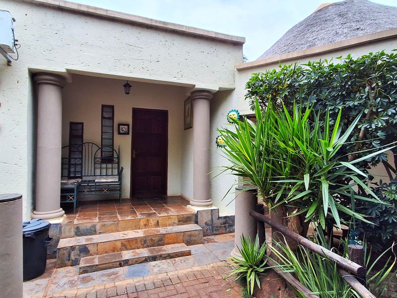 The front entrance of the lodge features a covered porch with stone columns, tiled steps, and a traditional thatched roof structure.