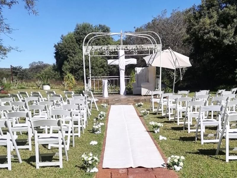 An outdoor garden area featuring a metal gazebo structure and a brick pathway, set within a landscaped lawn environment.
