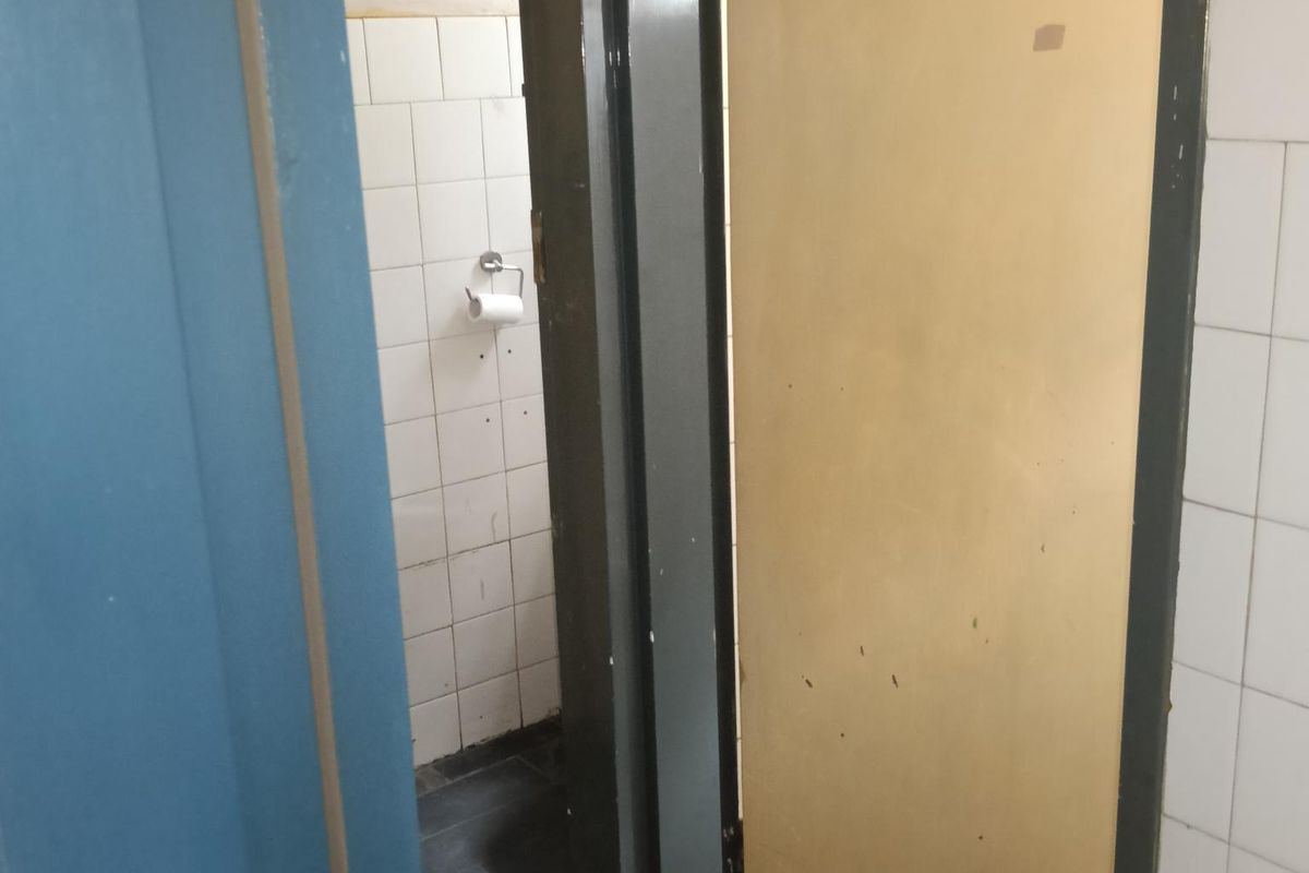 A small, dated bathroom or utility restroom featuring tiled walls and flooring, currently in need of maintenance and cosmetic updates.