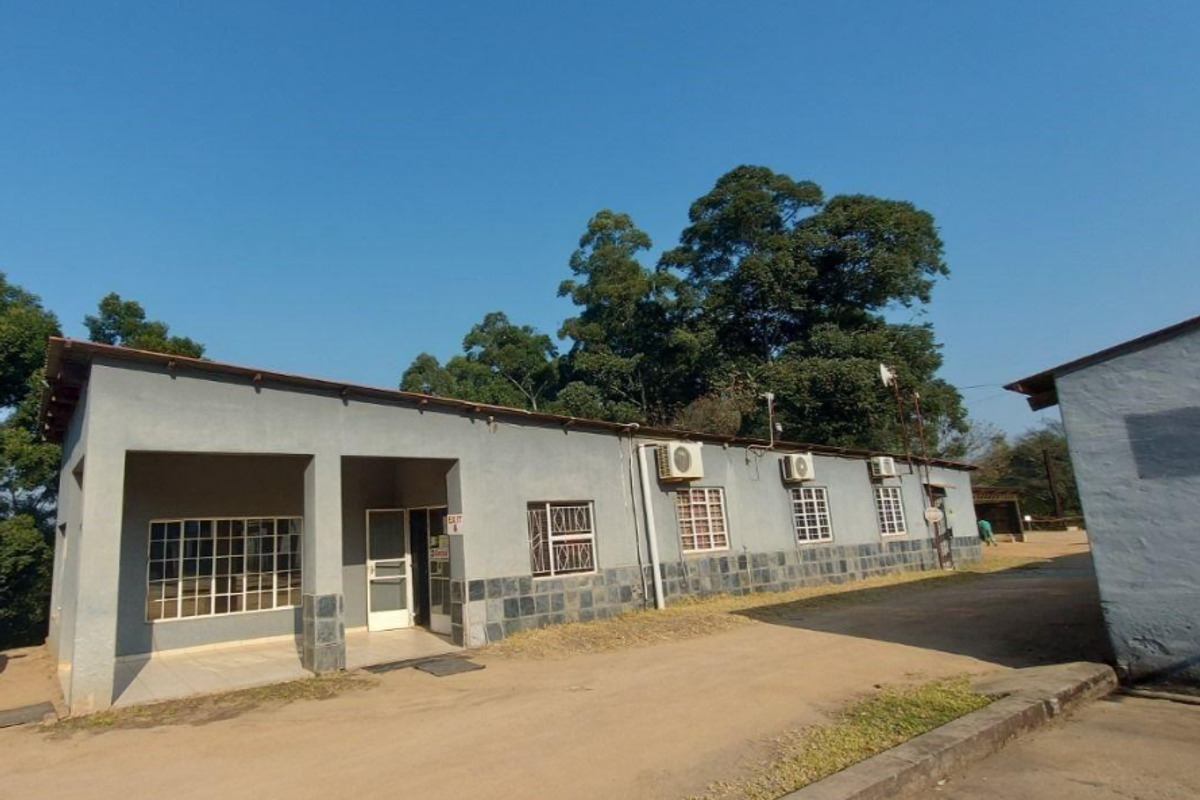 Exterior view of a commercial building featuring stone cladding, security bars on windows, and multiple wall-mounted air conditioning units.
