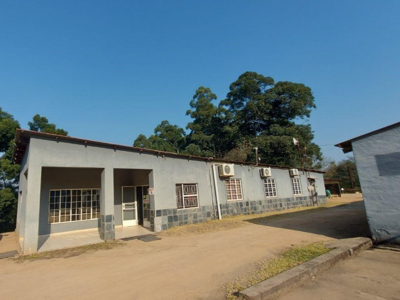 Exterior view of a commercial building featuring stone cladding, security bars on windows, and multiple wall-mounted air conditioning units.