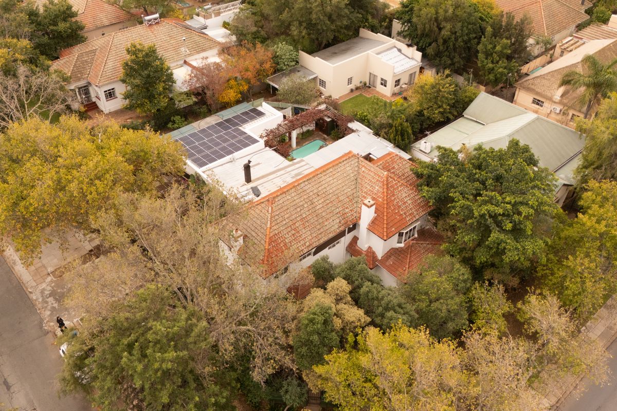 Aerial view of the property showcasing the main residence with terracotta roof tiles, solar panel installation, and a private swimming pool area.
