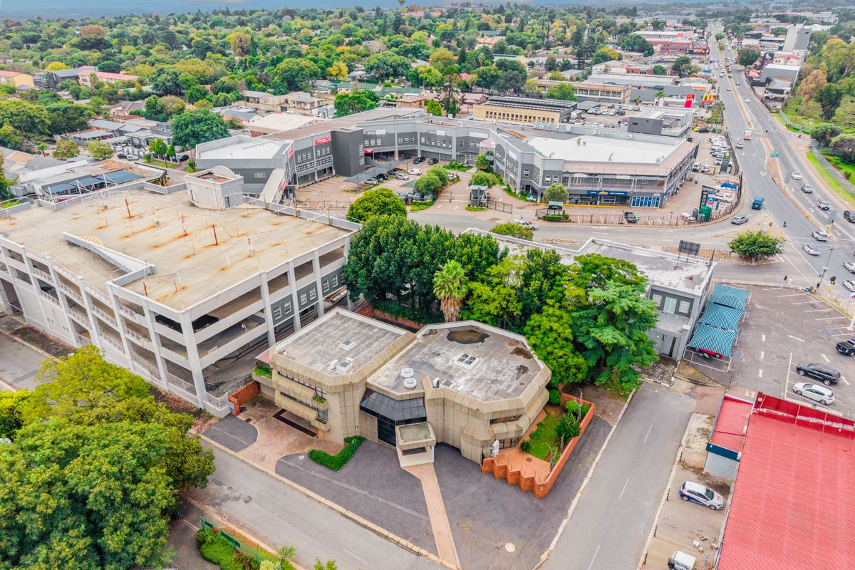 Aerial view of a multi-level office complex featuring a concrete facade, adjacent parking structure, and surrounding urban infrastructure.