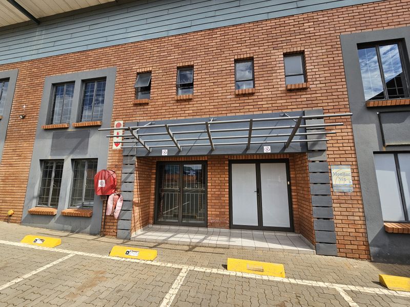 Front elevation of an industrial building featuring a brick facade, metal entrance awning, and dedicated paved parking bays.