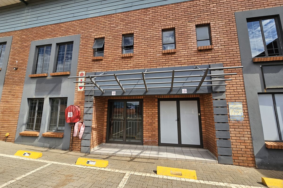 Front elevation of an industrial building featuring a brick facade, metal entrance awning, and dedicated paved parking bays.