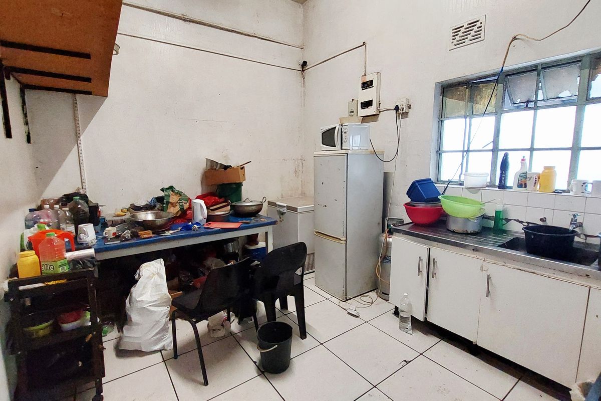 A functional kitchen area featuring tiled flooring, a stainless steel sink, and basic cabinetry, currently requiring maintenance and cosmetic updates.