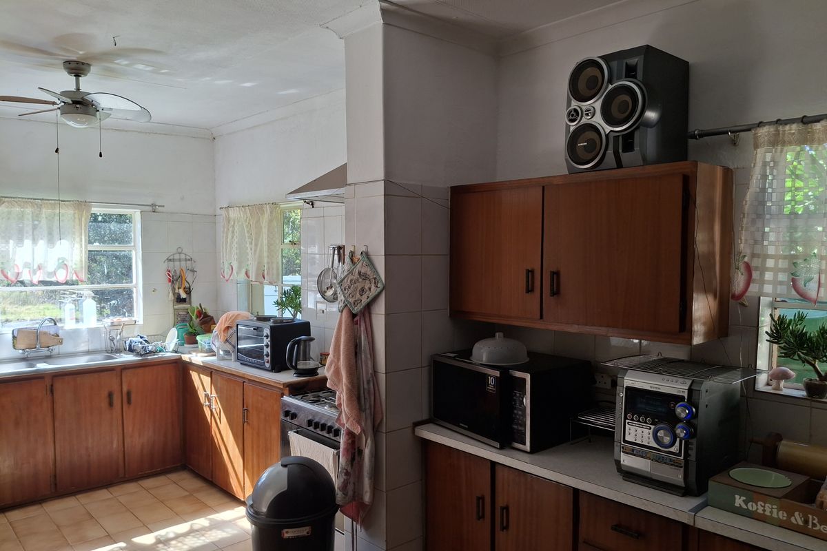 A functional kitchen featuring wooden cabinetry, tiled flooring, and a built-in sink, offering a classic layout with potential for modern updates.