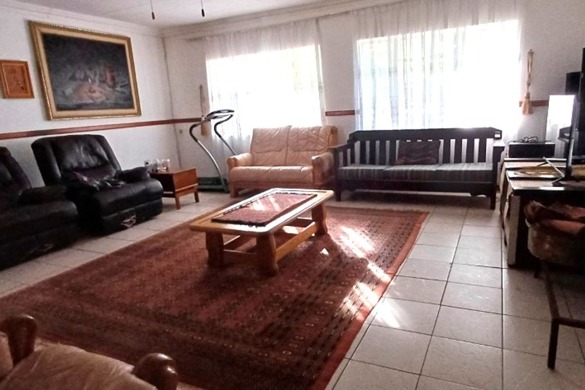A spacious living room featuring tiled flooring and a decorative dado rail, offering a functional layout with ample natural light.
