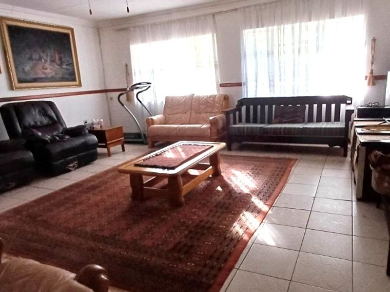 A spacious living room featuring tiled flooring and a decorative dado rail, offering a functional layout with ample natural light.