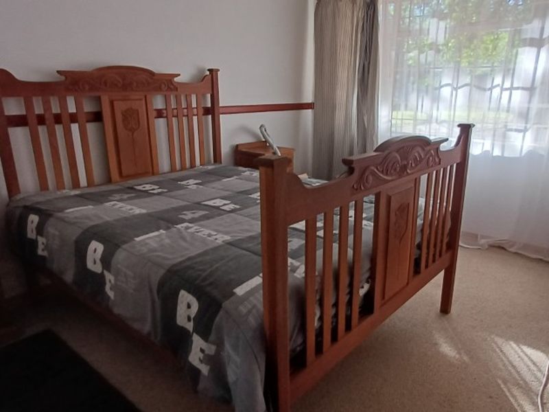 A standard bedroom featuring carpeted flooring and large windows with curtain rails, providing natural light and a functional living space.
