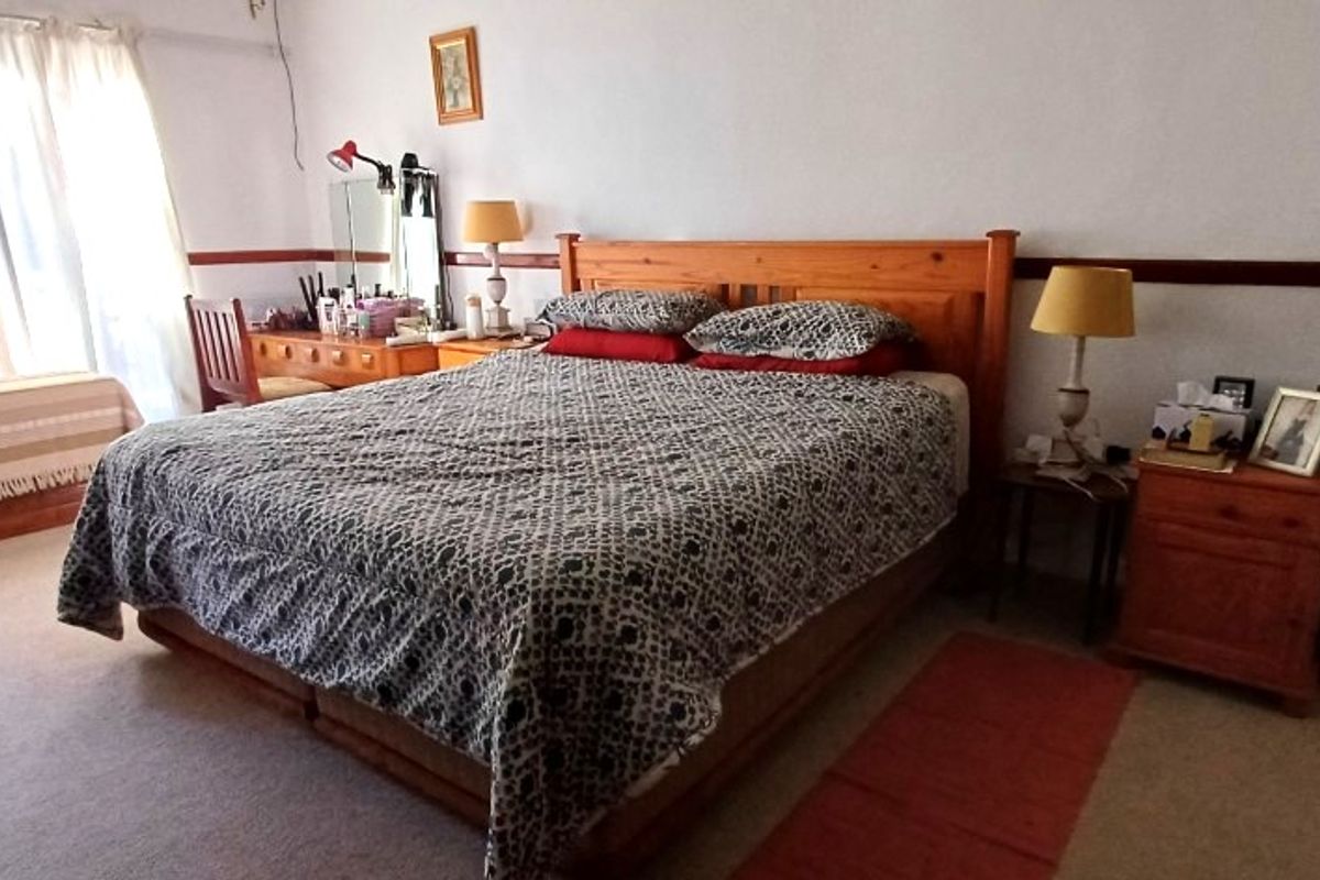 A spacious bedroom featuring neutral walls, a wooden dado rail, and carpeted flooring, offering a comfortable and functional living space.