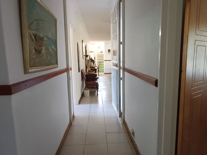 A functional interior hallway featuring tiled flooring and a wooden dado rail, providing access to adjacent rooms within the property.