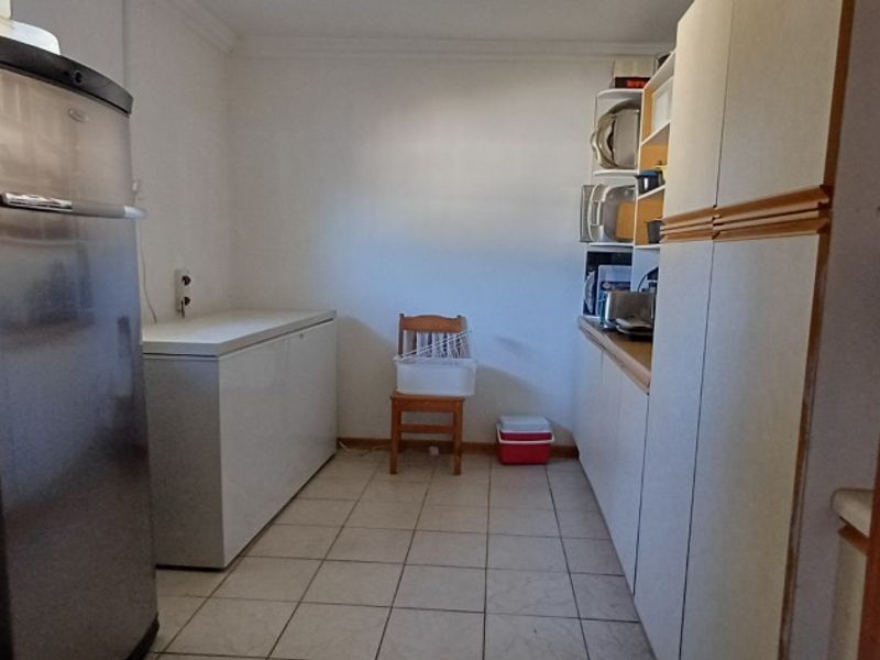 A functional scullery area featuring built-in cabinetry, tiled flooring, and ample space for utility appliances.
