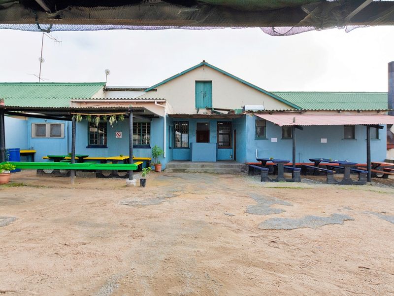 Rear exterior view of the restaurant building featuring a large open courtyard area with covered patio sections and a weathered facade.