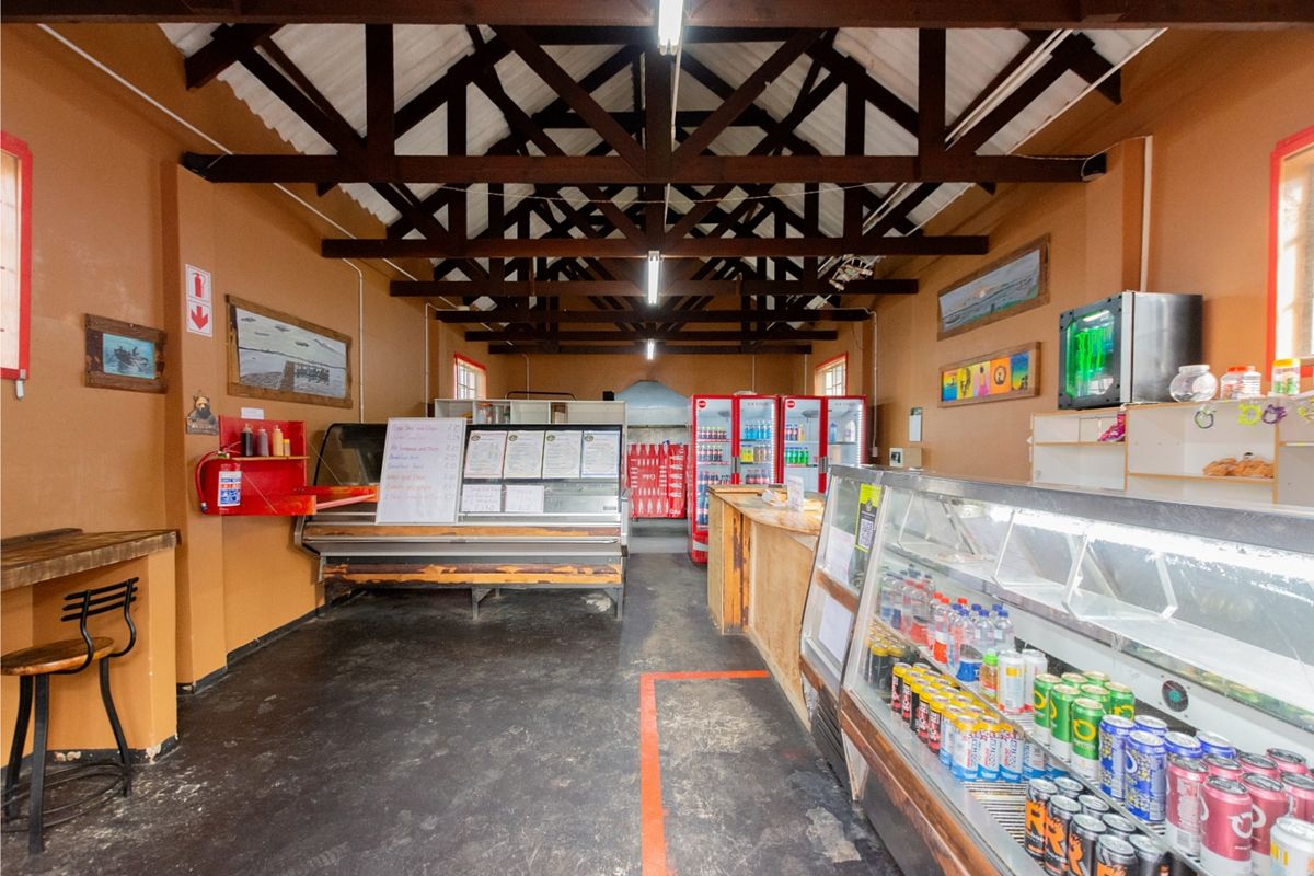 Commercial kitchen and service area featuring exposed timber roof trusses, built-in service counters, and integrated display refrigeration units.