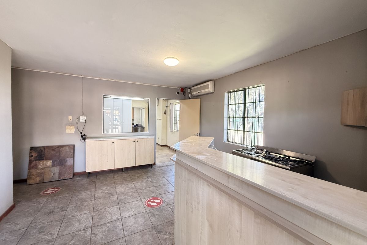 A functional kitchen area featuring a built-in service counter, gas hob, cabinetry, and tiled flooring, suitable for industrial or commercial use.