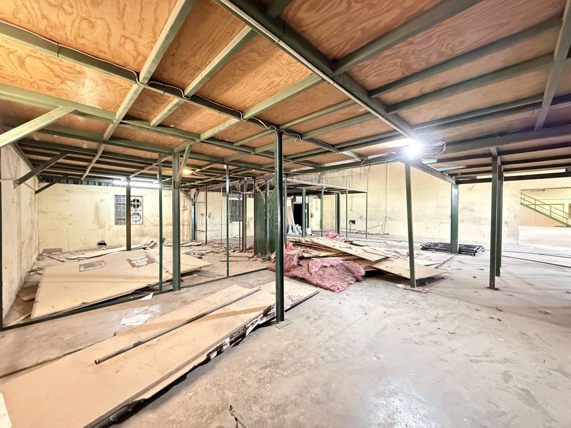 Large industrial warehouse space featuring an exposed steel mezzanine structure, concrete flooring, and open-plan layout suitable for storage or workshop conversion.