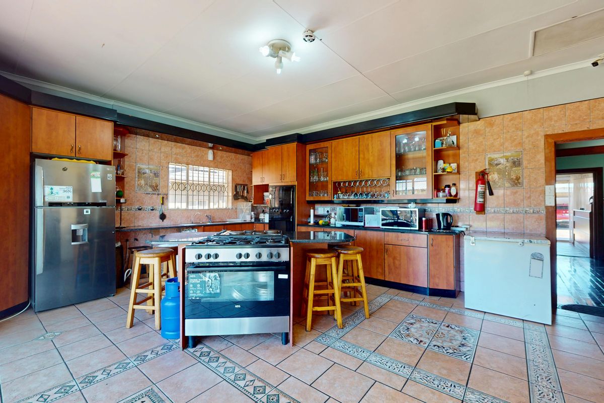 Spacious kitchen featuring wooden cabinetry, a central island with a gas stove, tiled flooring, and a tiled backsplash.
