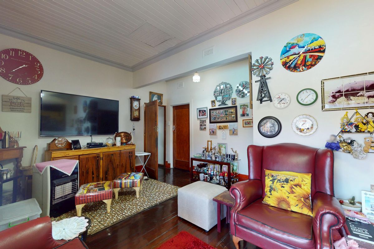 A living room featuring polished timber flooring, tongue and groove ceiling, and traditional timber door frames.