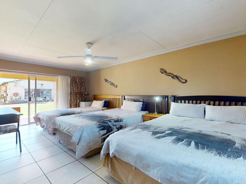 A spacious bedroom featuring ceramic floor tiles, a ceiling fan, and a sliding glass door providing direct access to the exterior.