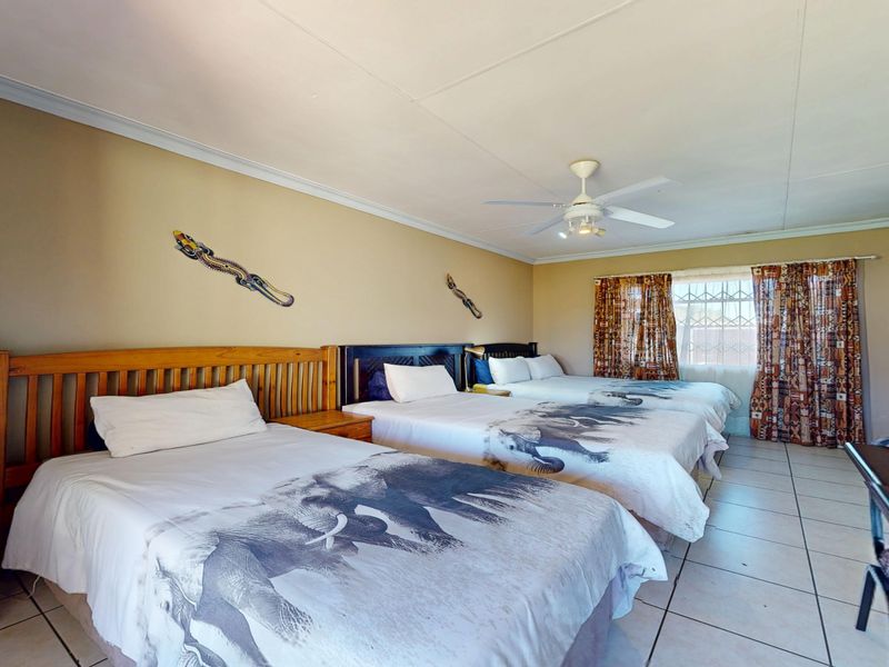 Spacious bedroom featuring tiled flooring, a ceiling fan, and a sliding door providing access to the exterior.