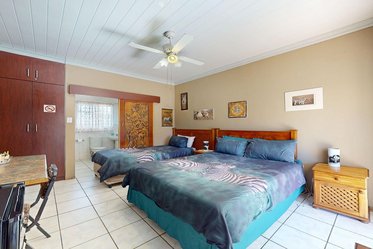 Spacious bedroom featuring tiled flooring, built-in cupboards, a ceiling fan, and direct access to an en-suite bathroom.