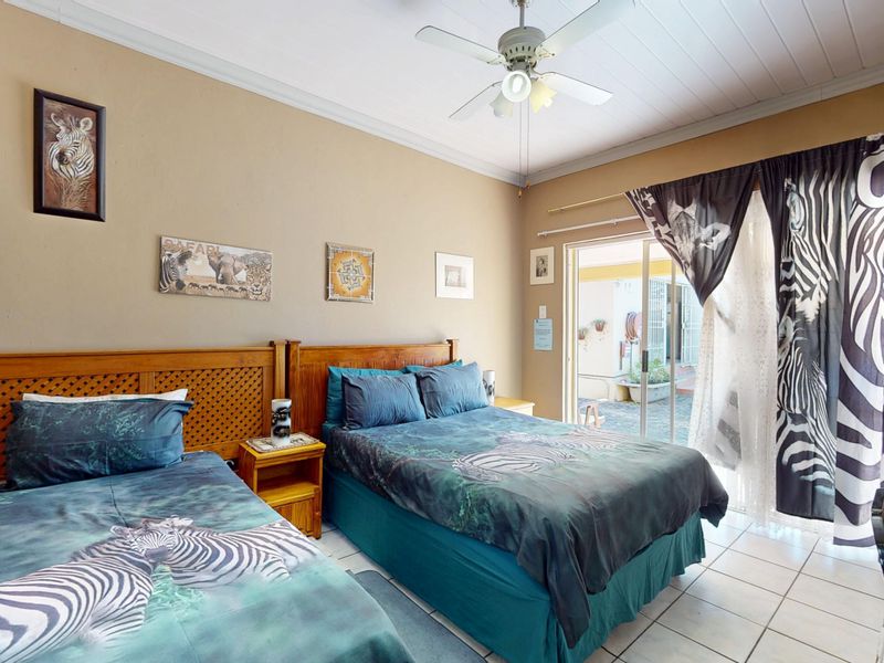 A bedroom featuring tiled flooring, a ceiling fan, and a sliding glass door providing direct access to an outdoor patio area.