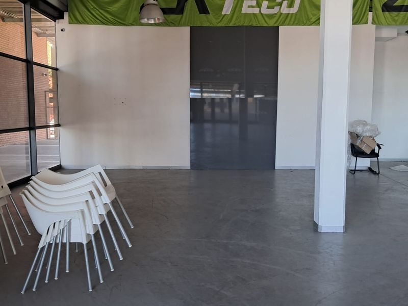 Spacious open-plan industrial unit featuring polished concrete floors, large glass windows, and high ceilings, suitable for a showroom or office workspace.