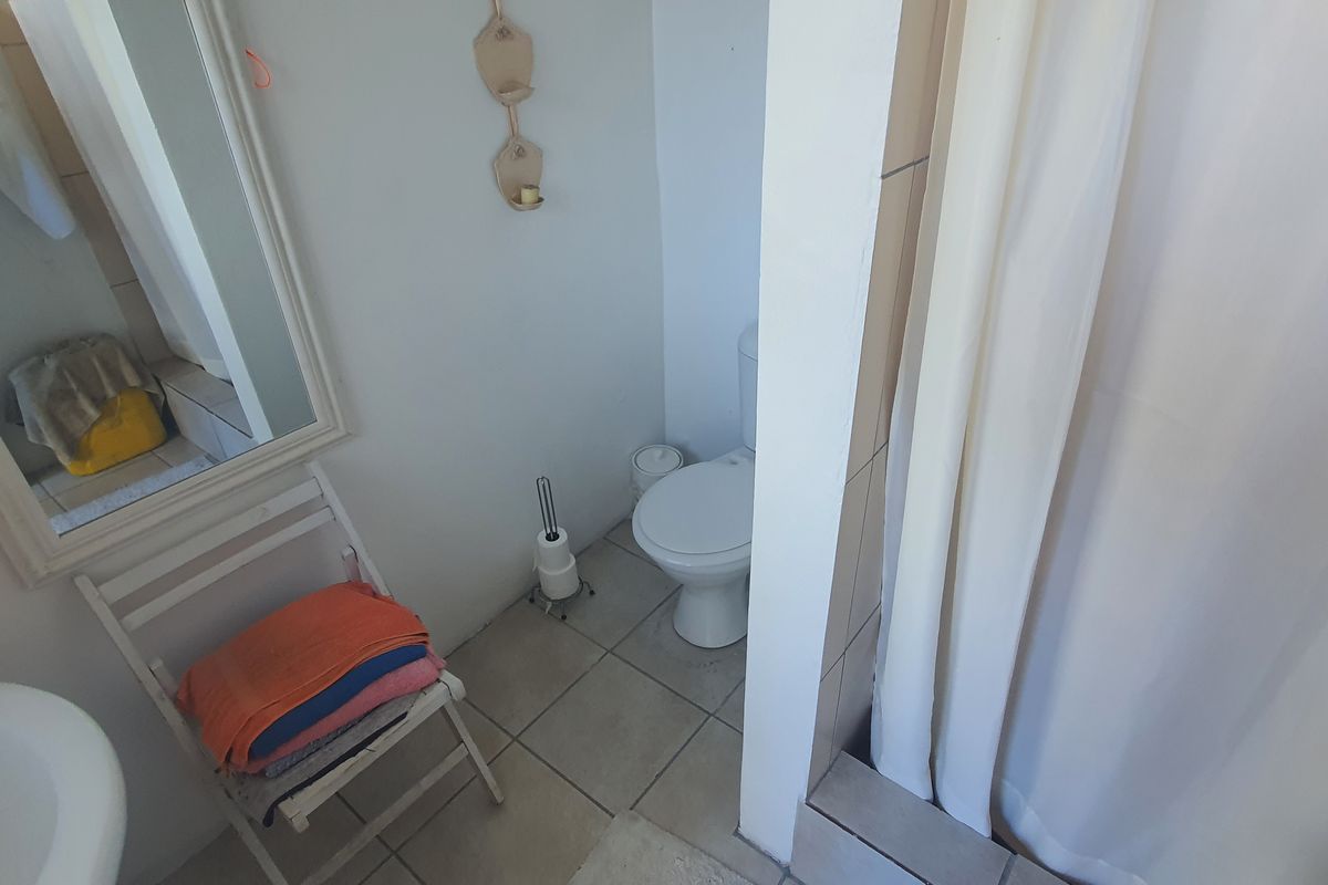 A functional bathroom featuring tiled flooring, a standard toilet, and a shower area with a curtain.