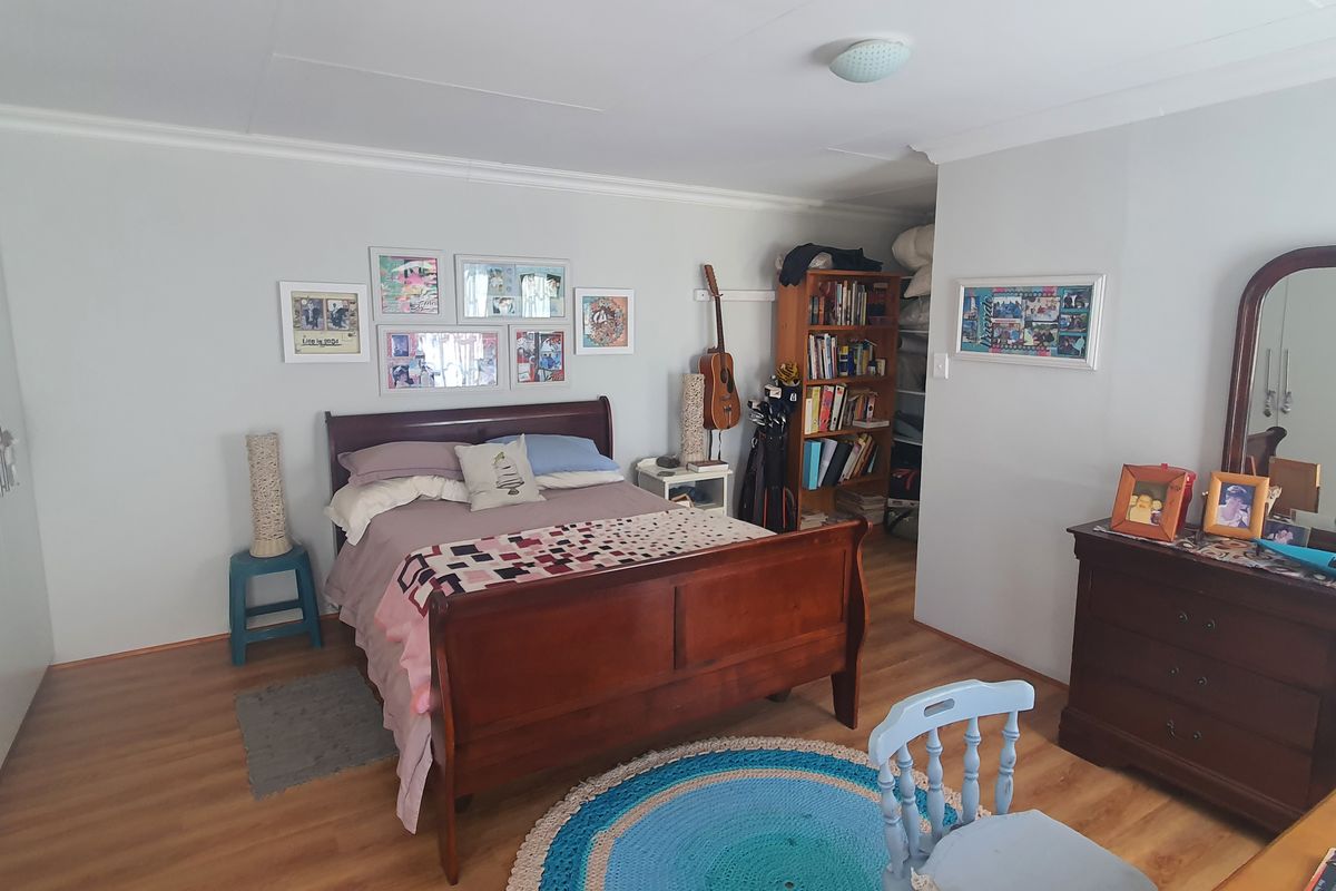 A spacious bedroom featuring laminate flooring, coved ceilings, and extensive built-in cupboard storage.