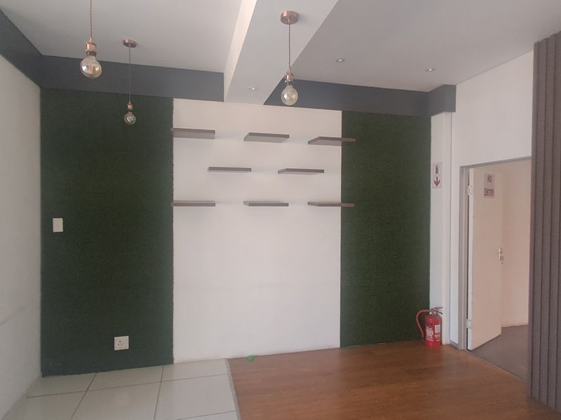 Modern interior space featuring a combination of laminate and tiled flooring, decorative wall paneling, floating display shelves, and contemporary pendant lighting.