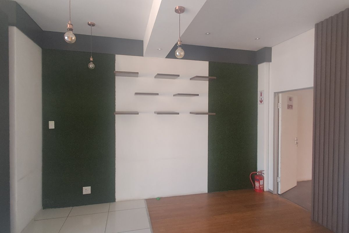 Modern interior space featuring a combination of laminate and tiled flooring, decorative wall paneling, floating display shelves, and contemporary pendant lighting.