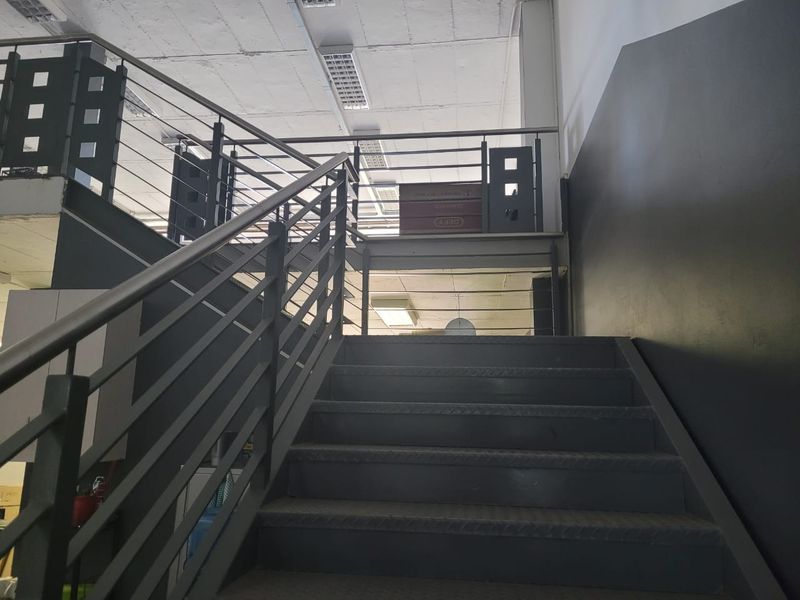 Industrial style interior staircase featuring metal steps and a matching metal balustrade leading to an upper level.