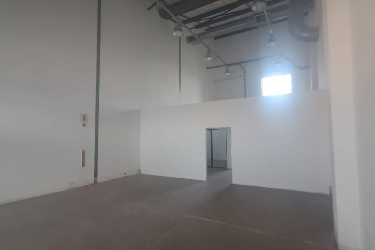 Spacious industrial utility area featuring high ceilings, exposed lighting fixtures, and durable concrete flooring, suitable for various commercial or storage applications.