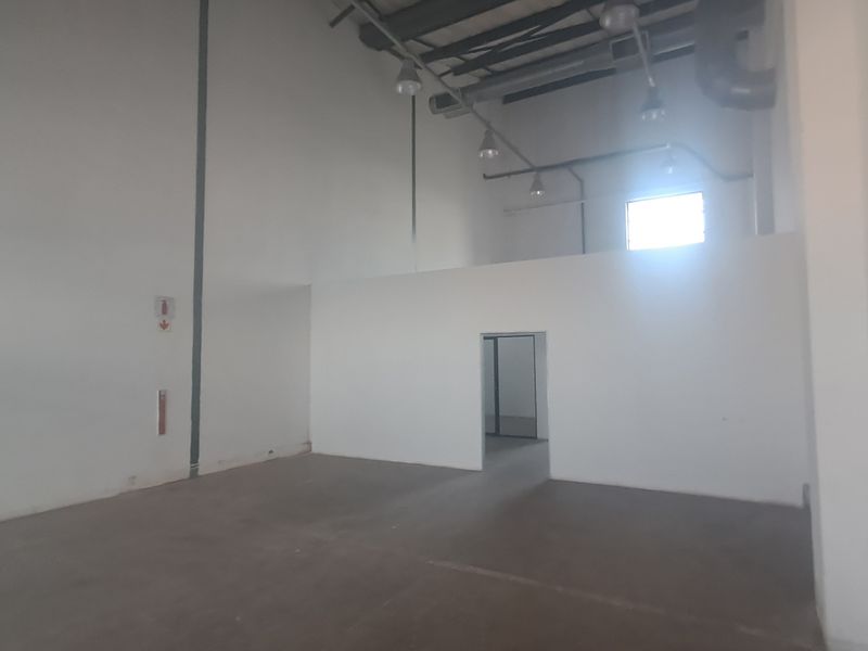 Spacious industrial utility area featuring high ceilings, exposed lighting fixtures, and durable concrete flooring, suitable for various commercial or storage applications.