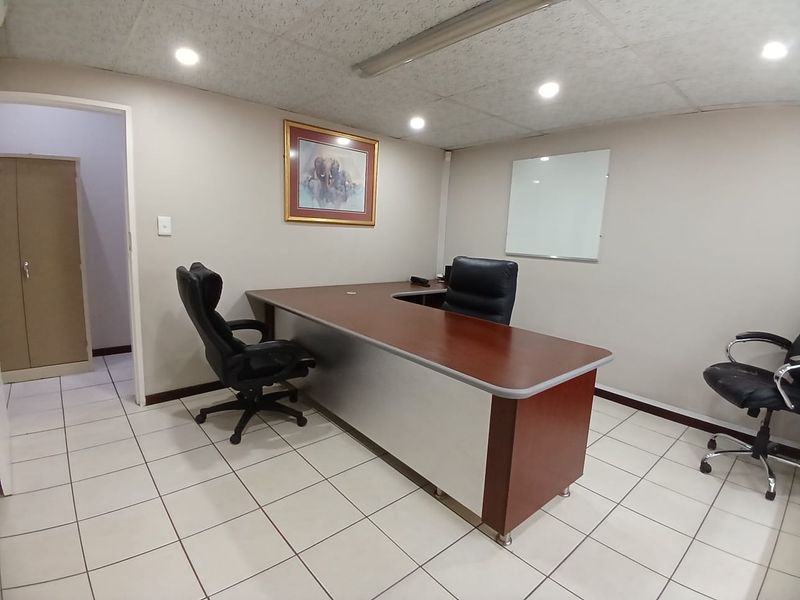 A functional commercial office space featuring ceramic tiled flooring, acoustic ceiling tiles, recessed lighting, and a built-in storage cupboard.