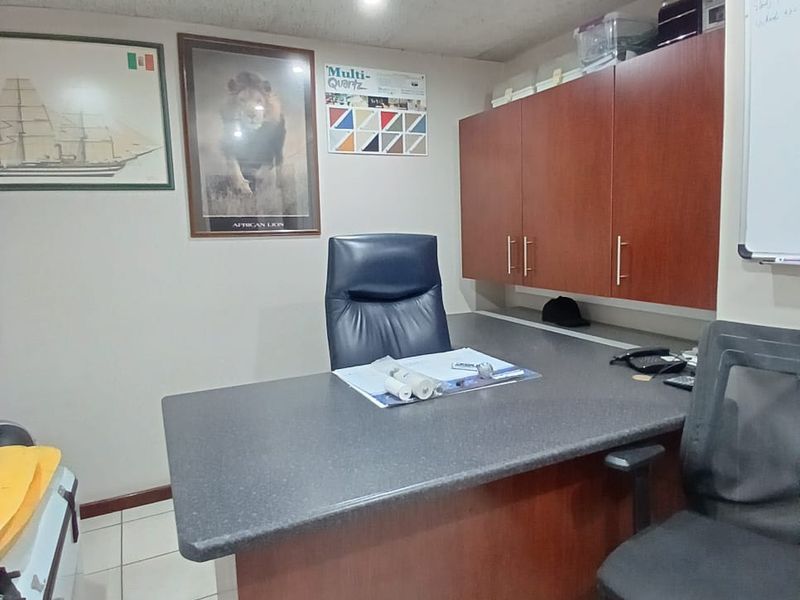 A functional office space featuring built-in wooden cabinetry, tiled flooring, and recessed lighting, providing a practical workspace environment.