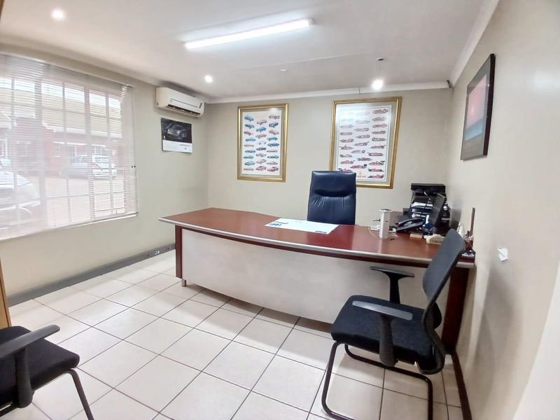 A functional commercial office space featuring tiled flooring, recessed lighting, and a wall-mounted air conditioning unit.